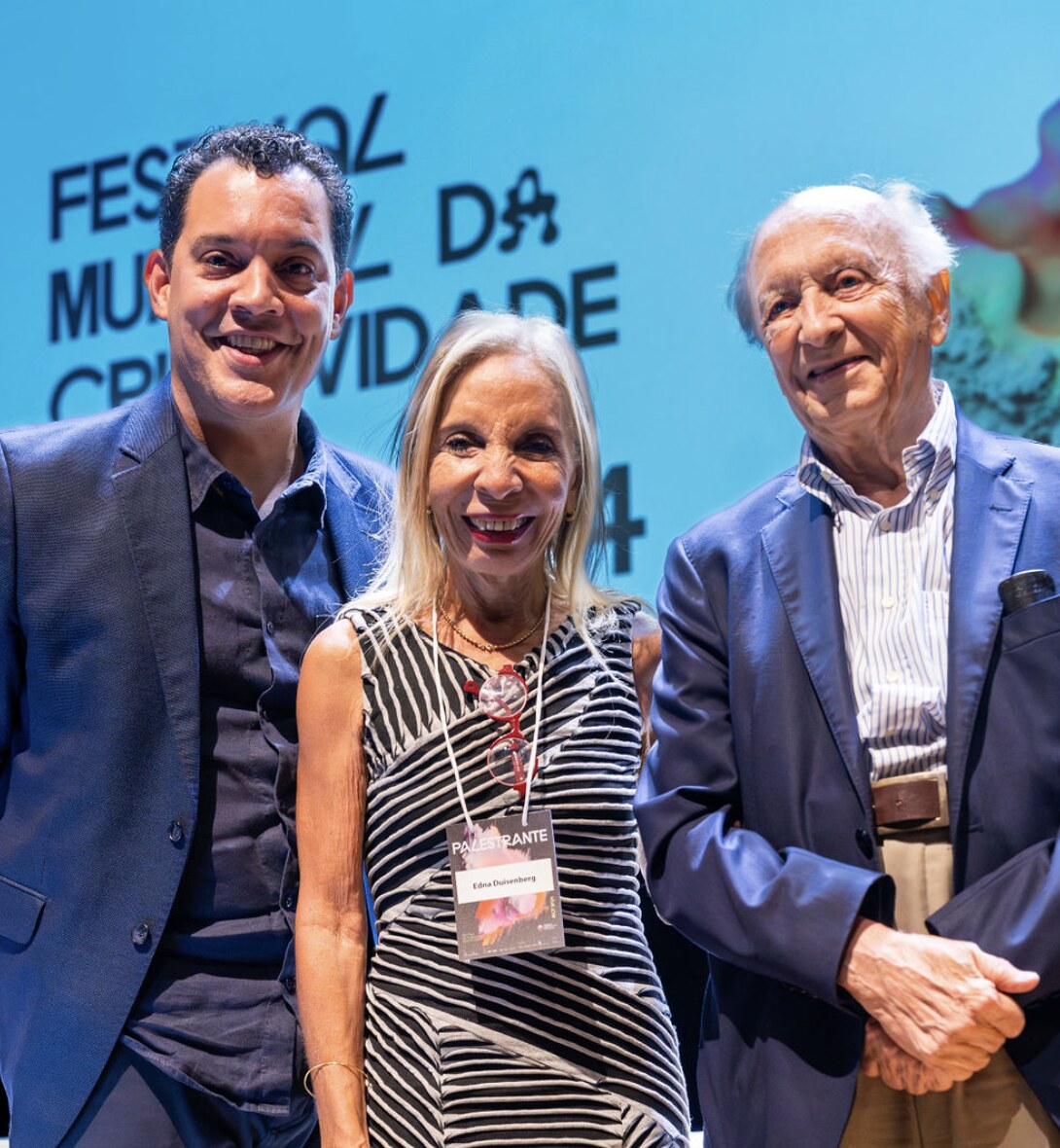 Three people posing together on stage at the Festival Mundial da Criatividade